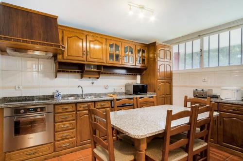a kitchen with wooden cabinets and a table and chairs at GuestReady - Comfortable Retreat in Esposende in Marinhas