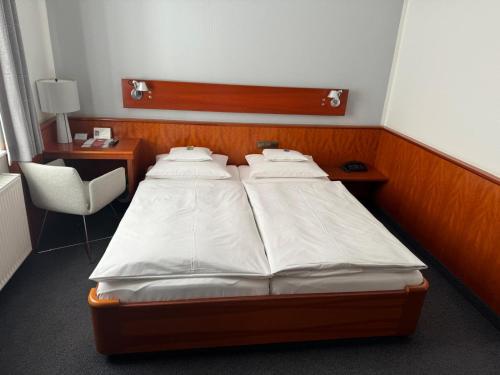 a bedroom with two beds and a chair at Historik Hotel Garni Christinenhof in Hameln