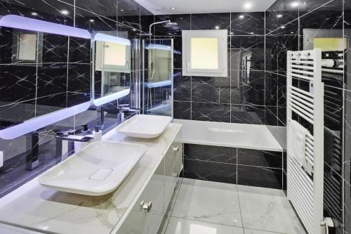 La salle de bains est pourvue de carrelage noir, de deux lavabos et de toilettes. dans l'établissement Villa Collonges, à Collonges-au-Mont-dʼOr