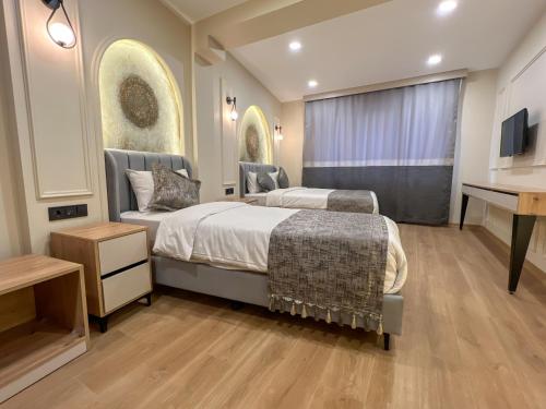 a bedroom with two beds and a desk and a television at Tophane Mansion Karakoy in Istanbul