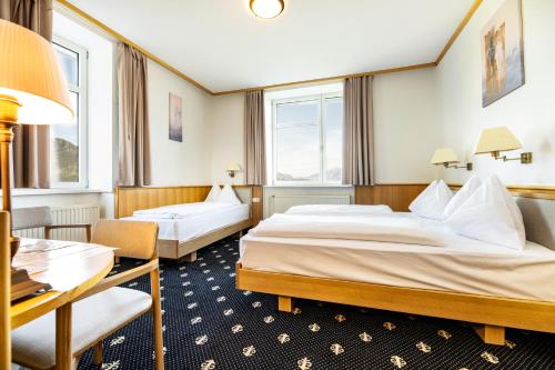 a hotel room with two beds and a desk at Sporthotel am Semmering in Semmering