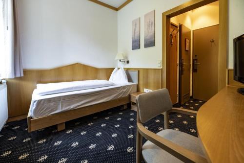 a bedroom with a bed and a table and a chair at Sporthotel am Semmering in Semmering