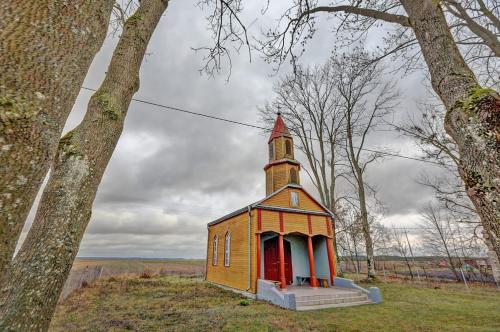 a small church with a red door in a field at Okoń in Sztabin