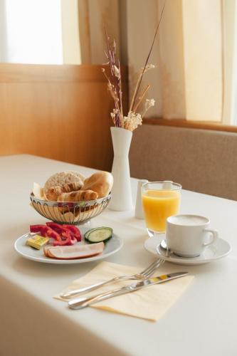a table with a plate of bread and a cup of orange juice at Sporthotel am Semmering in Semmering