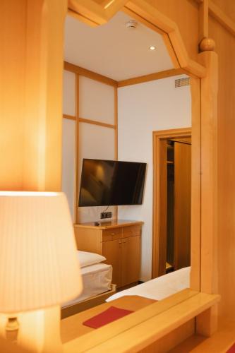 a bedroom with a mirror and a tv and a bed at Sporthotel am Semmering in Semmering