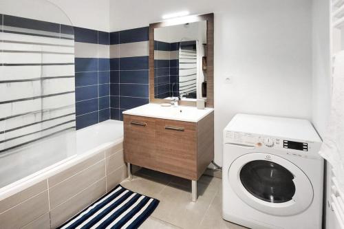 une salle de bain avec une machine à laver et un lavabo dans l'établissement Pixell Grand Lyon, à Villeurbanne