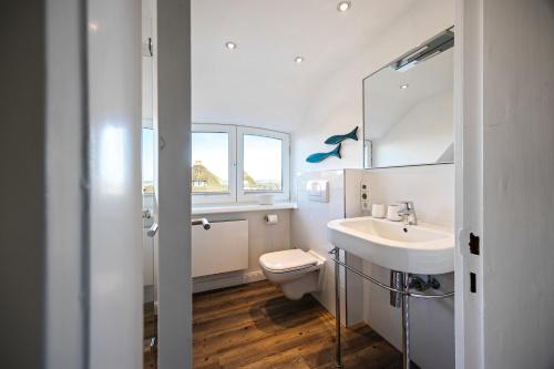 a white bathroom with a toilet and a sink at Haus Sonnenland in Hörnum