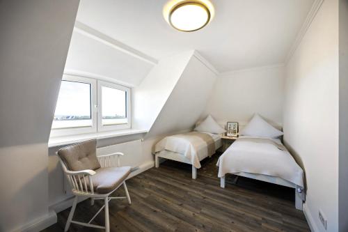 a attic bedroom with two beds and a chair at Haus Sonnenland in Hörnum