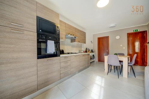 a kitchen with a table and a tv on the wall at Penthouse in Mosta with city views & terrace by 360 Estates in Mosta