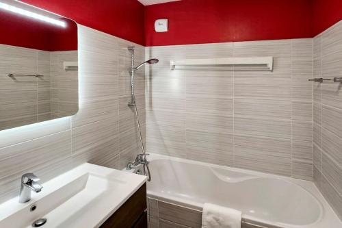 a bathroom with a white tub and red walls at Terrace Caluire in Caluire-et-Cuire
