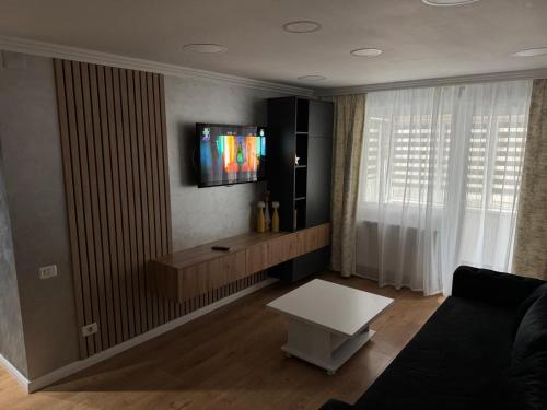 a living room with a couch and a tv on a wall at Apartament Narcisa in Bacău