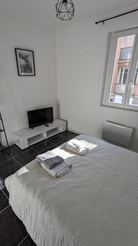 une chambre blanche avec un lit avec deux serviettes dessus dans l'établissement L'échappée, au Havre