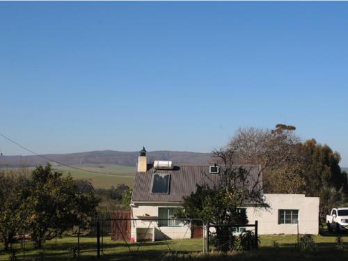 a white house with a roof on a field at Beloftebos Farm Cottages in Papiesvlei