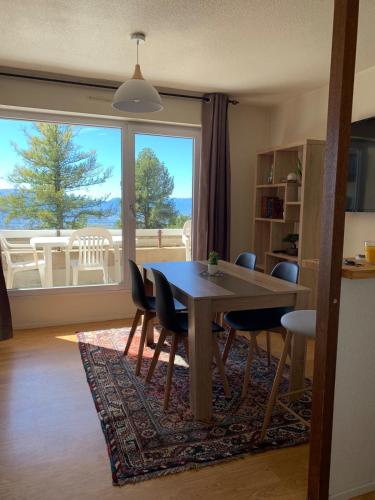 une salle à manger avec une table et des chaises et une grande fenêtre dans l'établissement Appartement Cosy Hypercentre vue sur les montagnes, à Font-Romeu-Odeillo-Via