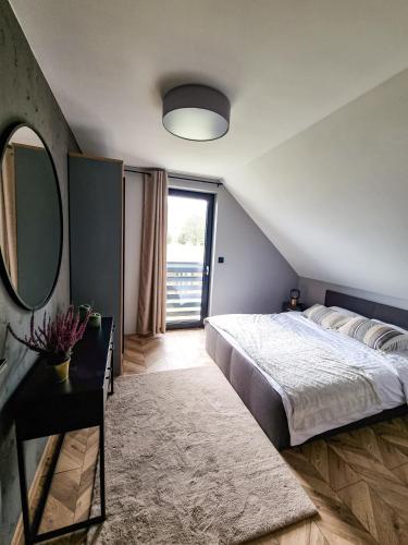 a bedroom with a large bed and a large window at TRZY SOSNY LOFT APARTMENTS in Ściegny