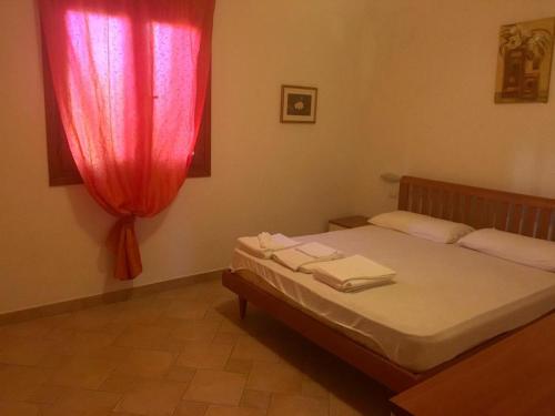 a bedroom with a bed with a red curtain at La Rosa dei Venti Residence in Monte Petrosu