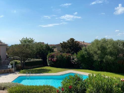 a swimming pool in a yard with bushes and trees at La Rosa dei Venti Residence in Monte Petrosu