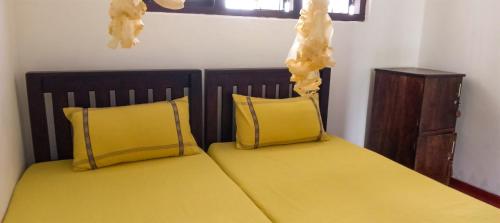 a bedroom with two beds with yellow pillows at Sharta Unawatuna Hostel in Unawatuna