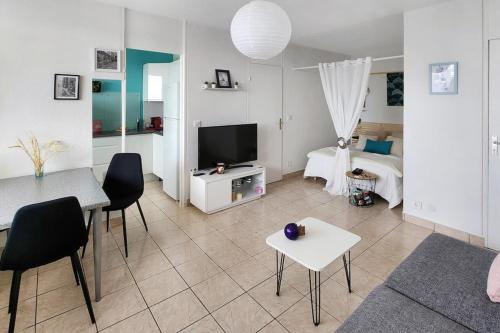un salon avec une télévision, une table et des chaises dans l'établissement City View, à Villeurbanne