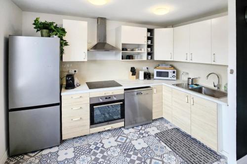 une cuisine avec des armoires blanches et un réfrigérateur en acier inoxydable dans l'établissement Eurexpo 3ch, à Bron