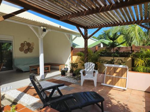 a patio with two chairs and a wooden pergola at Maison charmante à Sainte-Anne avec jardin et pergola en bois. in Sainte-Anne