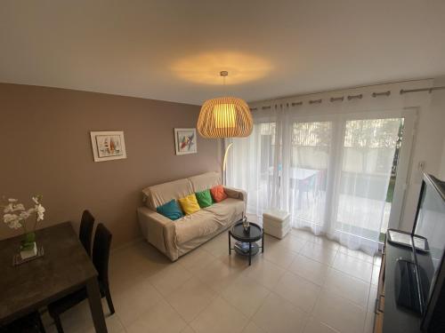 - un salon avec un canapé et un lustre dans l'établissement Les Roses Appartement 3 etoiles, à Les Sables-dʼOlonne