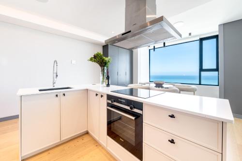a kitchen with white cabinets and a large window at Luxury Beachfront Penthouse, Blouberg- 3 Bedroom in Bloubergstrand