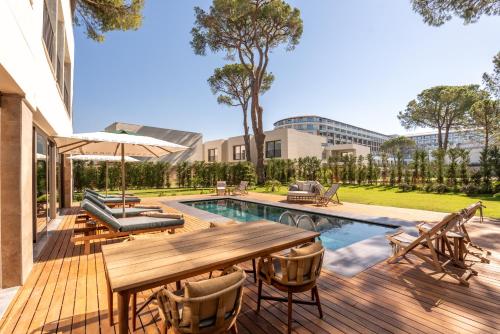 a wooden deck with a table and chairs next to a pool at Ethno Belek in Belek