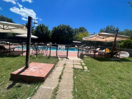 a pool with tables and umbrellas in a yard at Il Vecchio Mulino in Massa Martana