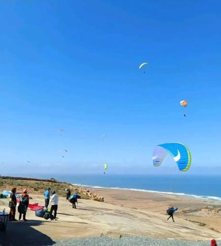 a group of people on a beach flying kites at Adoir N'salh in Tiznit