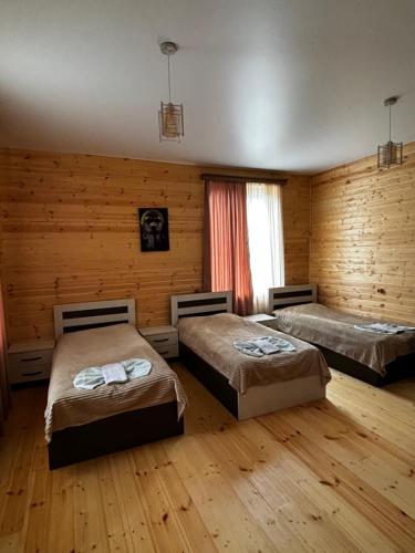 two beds in a room with wooden walls and wooden floors at Hotel okriba in Tqibuli