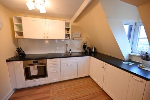 a kitchen with white cabinets and a black counter top at TÜRMERSTUBE - Scandi Style - in der historischen Hinterburg Schlitz - nahe Fulda in Schlitz