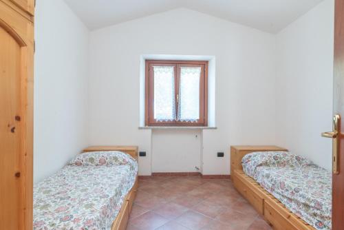 two beds in a room with a window at Marelò in Vignola Mare