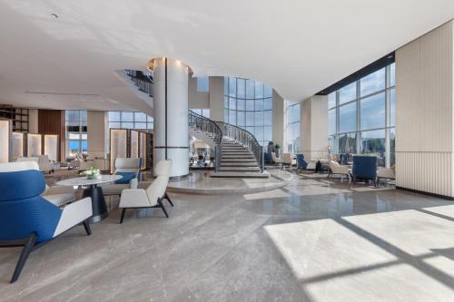 a lobby with chairs and tables and a staircase at Braira Hafar Al-Batin in Hafr Al Baten