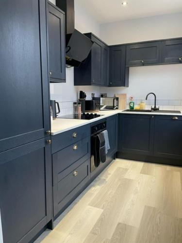 a kitchen with blue cabinets and a wooden floor at Brand New city Centre Flat, WiFi, Free Private off-site parking in Nottingham