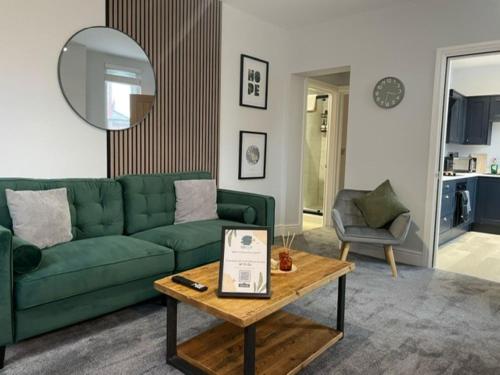 a living room with a green couch and a table at Brand New city Centre Flat, WiFi, Free Private off-site parking in Nottingham