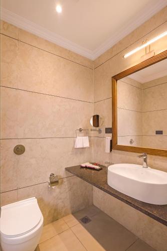 a bathroom with a sink and a toilet and a mirror at Sterling Rudraksh Jaisalmer in Jaisalmer