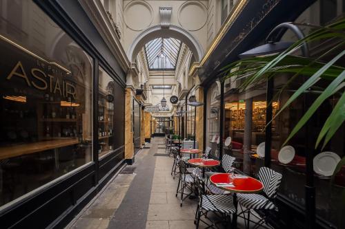 une allée vide avec des tables et des chaises dans un bâtiment dans l'établissement Vivienne by Sereners - Sublime Apartment near Opera, à Paris