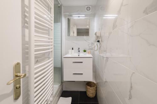 une salle de bain blanche avec un lavabo et une douche dans l'établissement Vivienne by Sereners - Sublime Apartment near Opera, à Paris