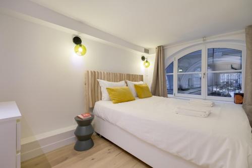 - un lit blanc avec des oreillers jaunes et une fenêtre dans l'établissement Vivienne by Sereners - Sublime Apartment near Opera, à Paris