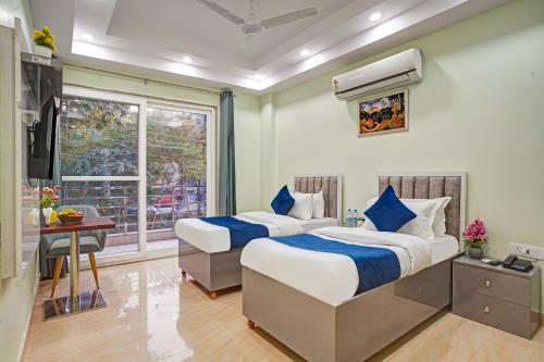 two beds in a room with a desk and a window at Hotel Durbar By Vardaan Residency in Gurgaon
