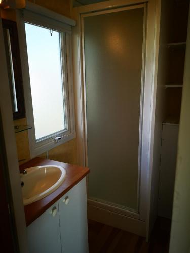 une salle de bain avec un lavabo et une fenêtre dans l'établissement Mobil Home 4 pers proche Puy du Fou et Montaigu (Vendée 85), à La Boissière-de-Montaigu