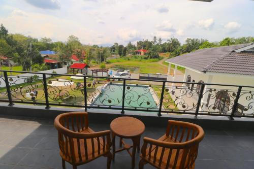 a balcony with two chairs and a table and a view at Grand Aeden Villa in Kuala Kangsar