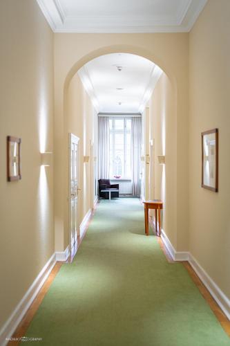 an empty hallway with a green carpet and a window at Schlosshotel Westerholt in Herten