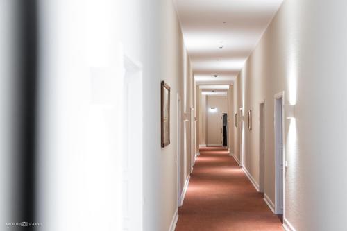 a hallway with white walls and a long hallway with paintings at Schlosshotel Westerholt in Herten