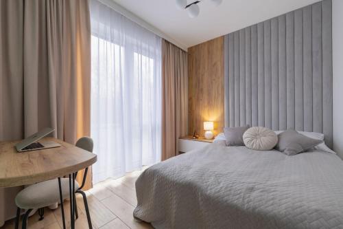 a bedroom with a bed and a desk with a computer at VIP Apartamenty Borowa in Rzeszów