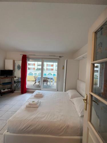 - une chambre avec un lit blanc et une porte coulissante en verre dans l'établissement La Terrasse de Palais des Arts, à Nice