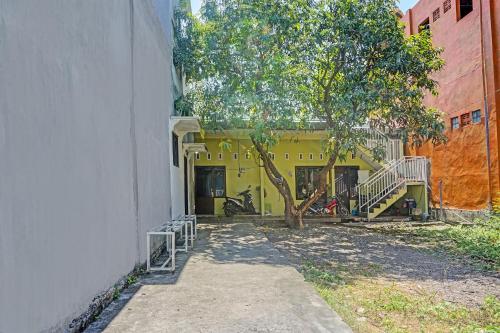 a yellow building with a tree in front of it at OYO Life 91600 Syariah Army Kost & Homestay in Gresik