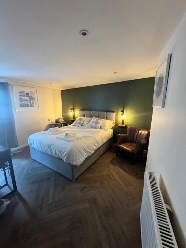 a bedroom with a large bed and a chair at The London Inn in Padstow