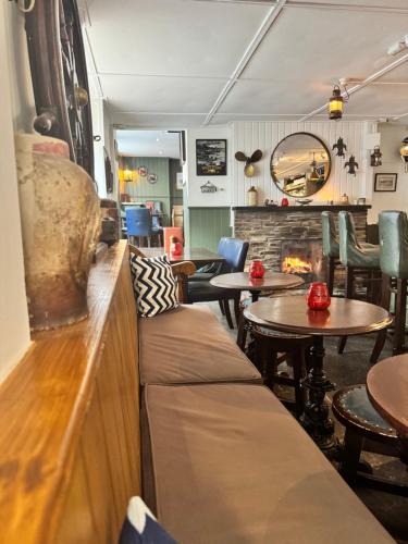 a restaurant with a couch and tables and a fireplace at The London Inn in Padstow